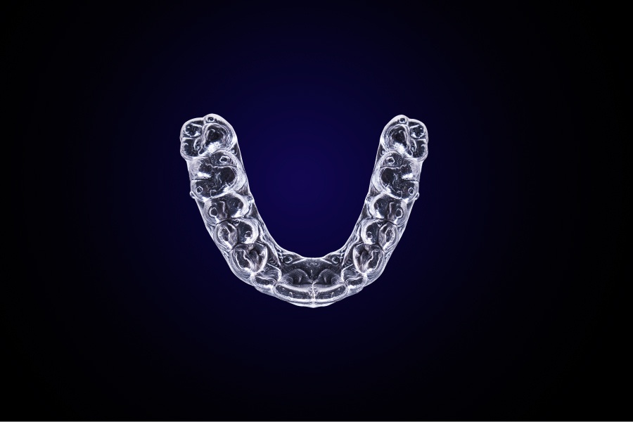 Aerial view of an Invisalign clear tray against a dark blue background
