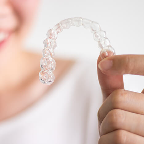 closeup of a person holding a set of Invisalign clear aligners