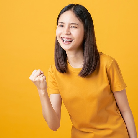girl with braces dressed in yellow smiling