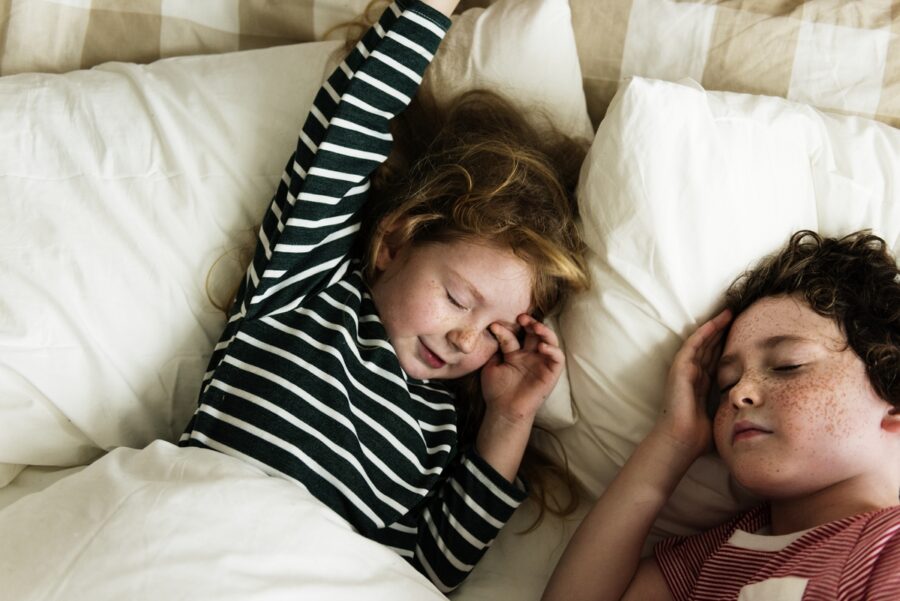 Two children sleep as they grind their teeth